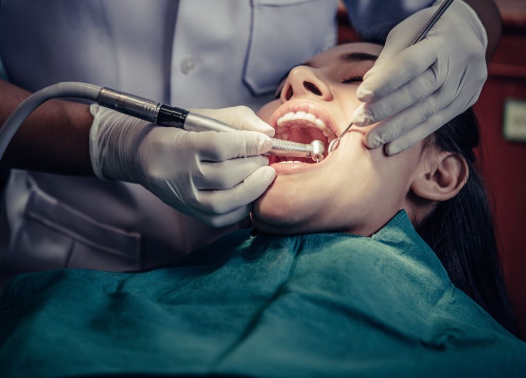 Dentist performing root canal treatment on patient using dental drill