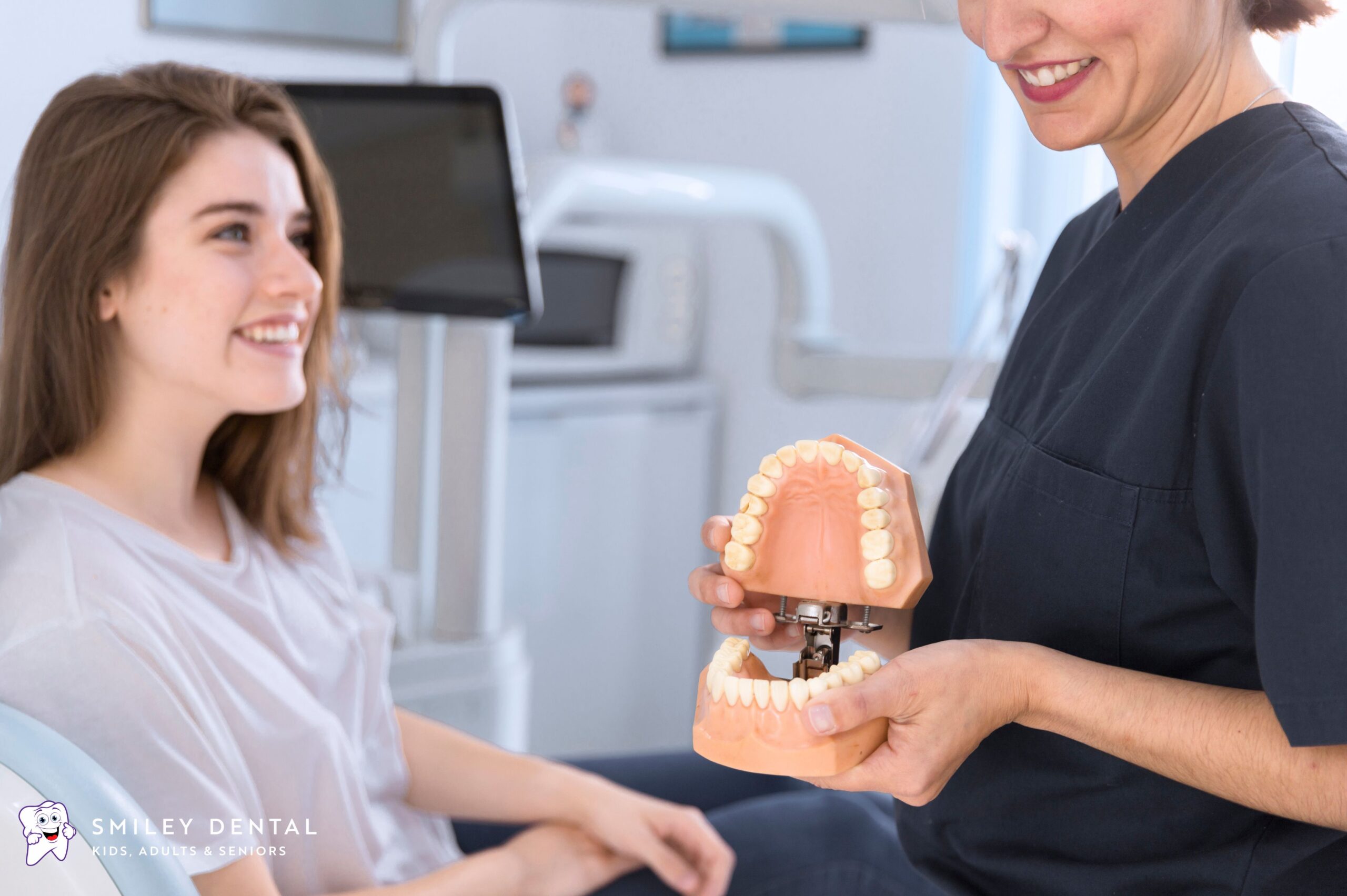 Smiley Dental Beverly dentist showing a patient a dental implant model during a consultation