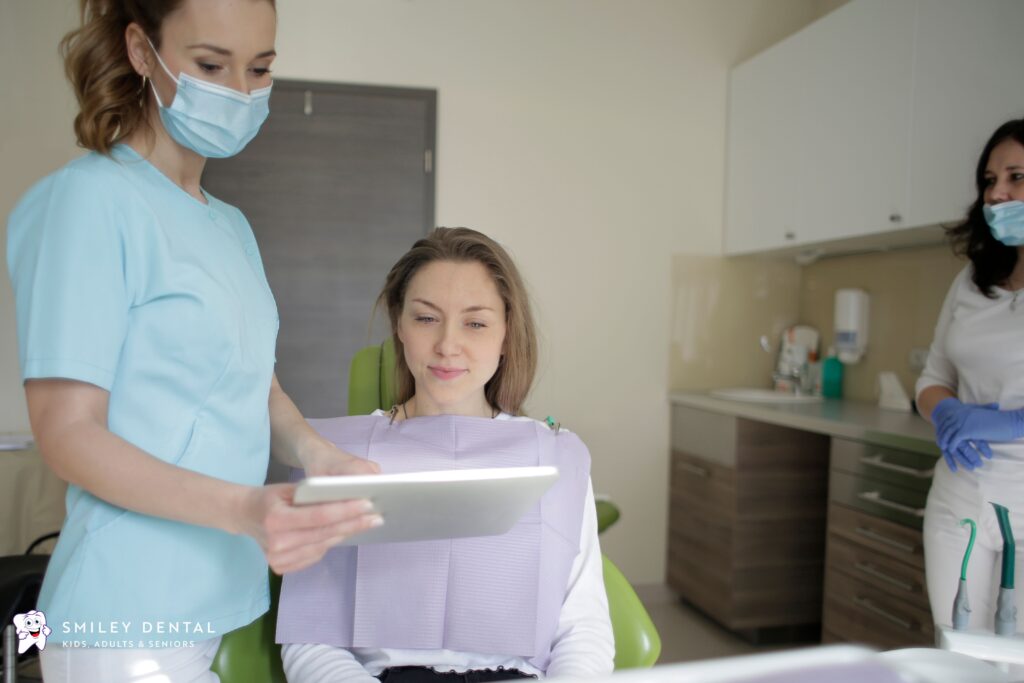 Dental hygienist reviewing treatment plan with patient on tablet at MassHealth dental office