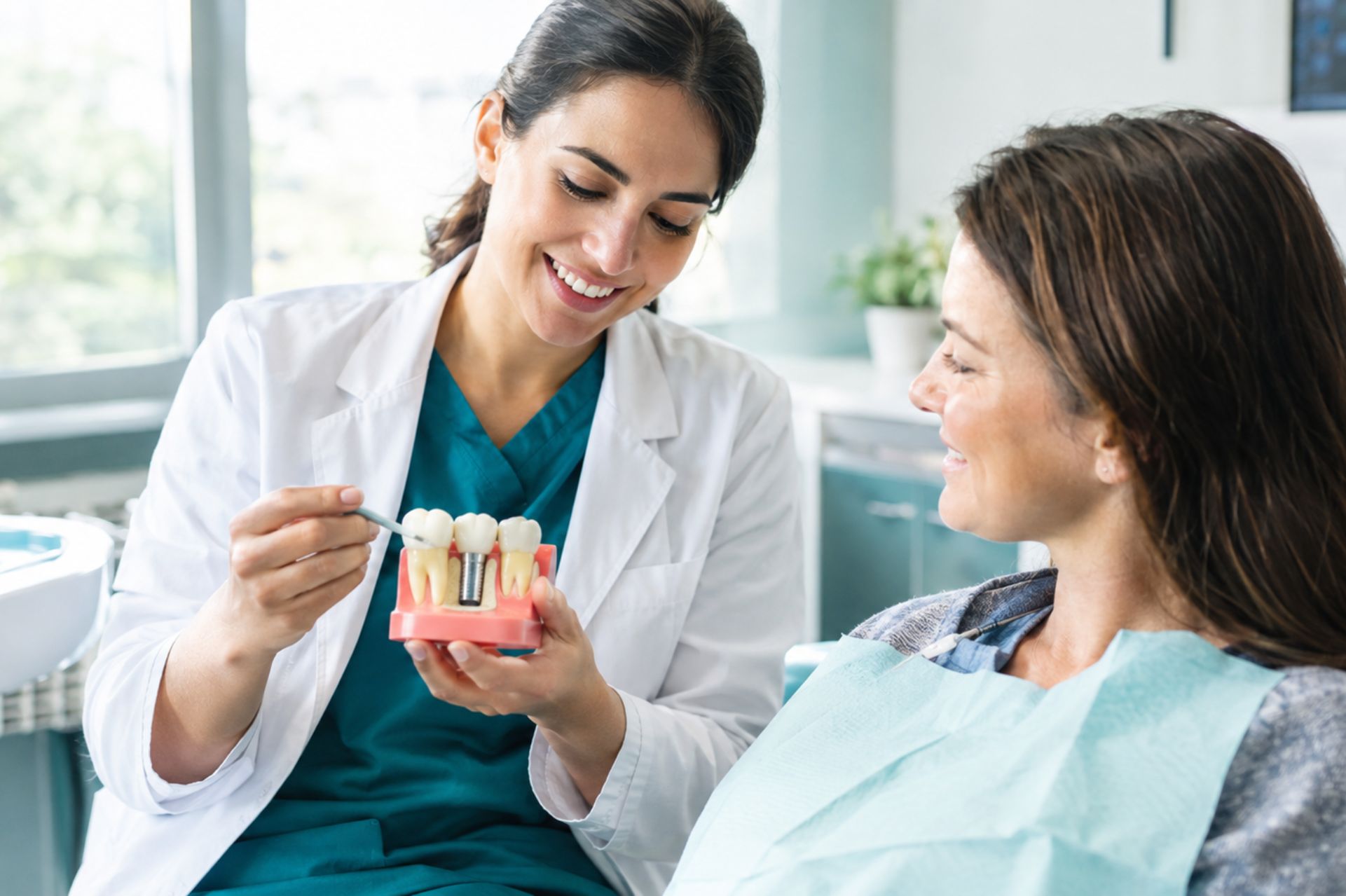 Dentist showing a tooth model to a patient during a preventive dental care consultation in Beverly, Massachusetts