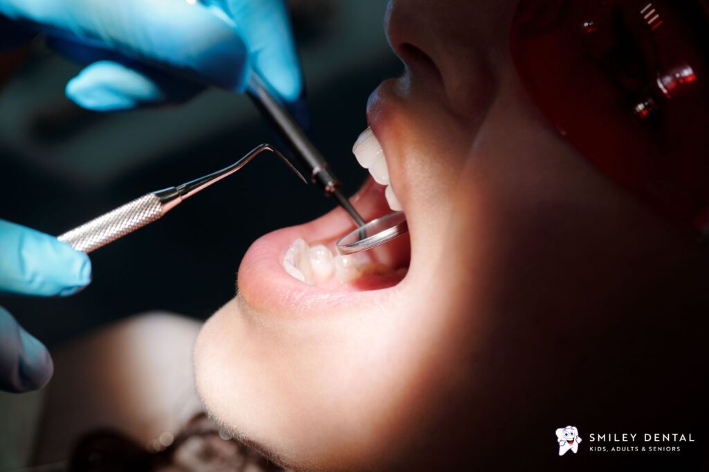 Dentist examining a patient's tooth with a mirror and dental explorer