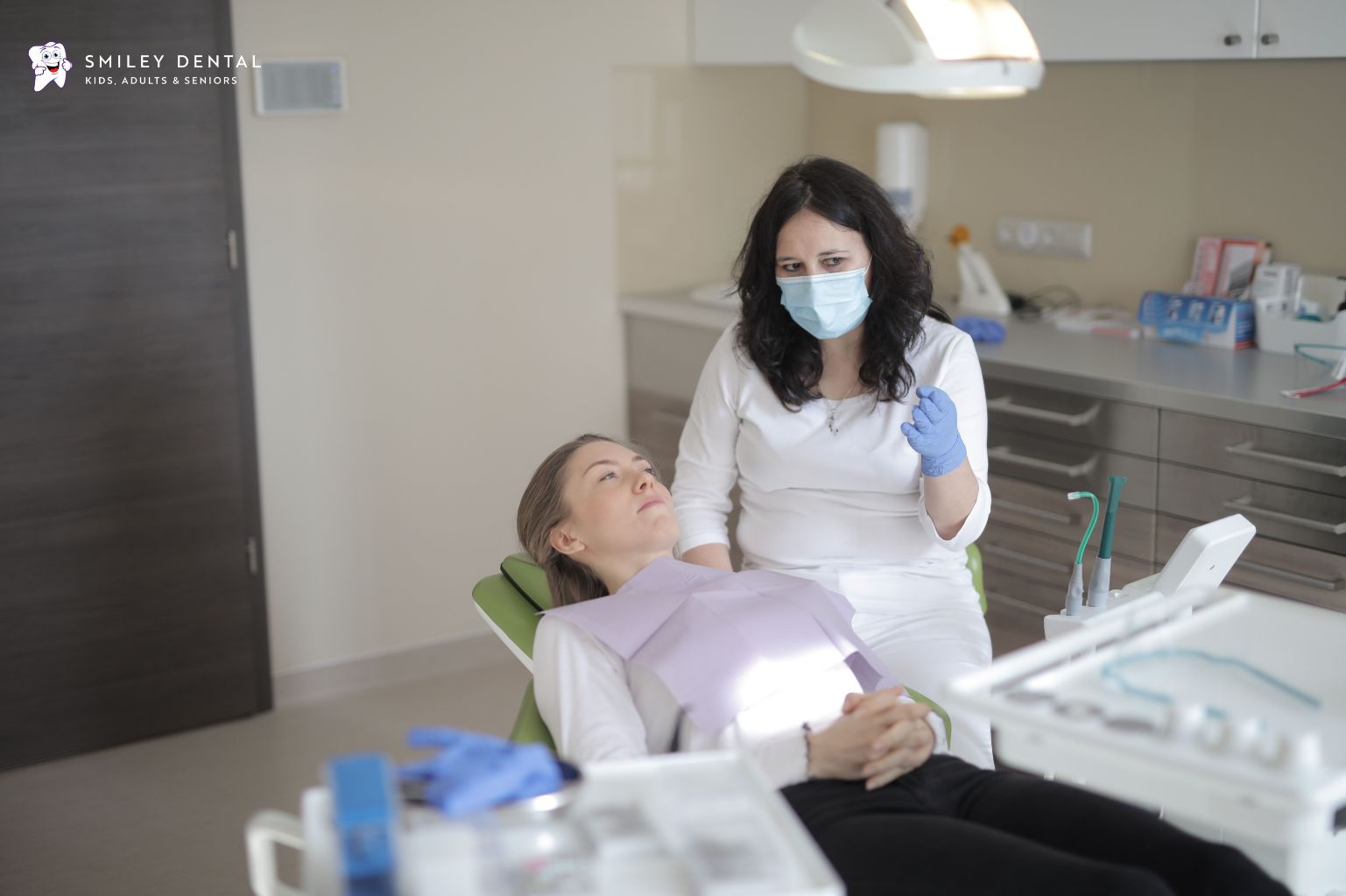 Dentist explaining treatment to a calm patient in a dental chair.